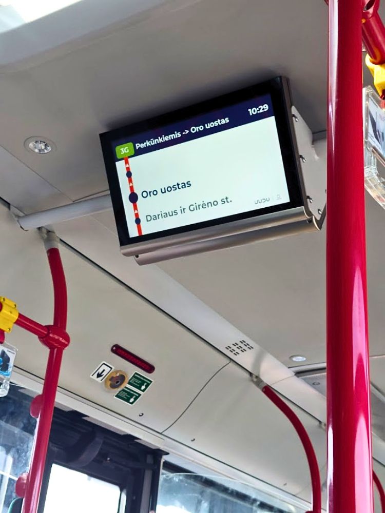 An onboard Vilnius public transport screen shows route 3G from "Perkūnkiemis" to "Oro uostas" with the time "10.29". The next stops shown from bottom to top are "Dariaus ir Girėno st." and "Oro uostas".